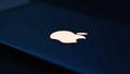 A close-up of a glowing Apple logo on a laptop screen amid a flurry of update pop-ups