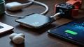 Close-up of a Belkin 25W Qi2 charger gleaming beside a phone, smartwatch, earbuds, and a tablet, all charging in harmonious chaos.