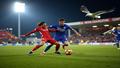 Destiny Udogie sliding into a tackle as Brighton players hover nearby, floodlights glaring, seagulls circling like judgmental referees in the night.