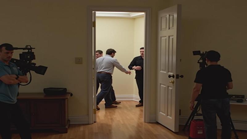 TV cameras circle the empty doorframe, capturing the moment a rumor squeezes through the laces.