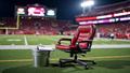 Empty interview chair on Lane Stadium’s 50-yard line, flanked by a lunch pail and a clipboard, under swirling Enter Sandman lights.