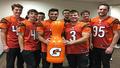 Back-of-the-roster hopefuls pose with a trophy-shaped Gatorade bottle in the Bengals' lounge, basking in their glorified snack-cart moment.