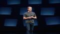 Mark Zuckerberg on a dark stage, haloed by screens, holding a sleek headset like a newborn business model.