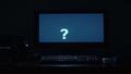 a dimly lit desk with a glowing monitor, a paused game, and a suspicious question mark floating over the keyboard.