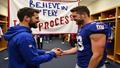 Jaxson Dart high-fives a Giants receiver while a 'Believe in the process' banner hangs in the locker room.