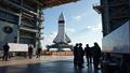 A gleaming Starship sits on the launch pad as engineers study a tangled whiteboard, while countdown clocks stubbornly refuse to agree.