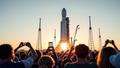 Super Heavy booster gliding to the pad, cranes flanking it like nervous prom chaperones, spectators framing the moment through phones and existential dread.