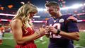 Taylor Swift and Travis Kelce exchanging a glittering ring amid stadium lights and sideline Gatorade, confetti hovering like a nervous flock of sponsorships.