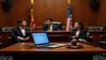 Courtroom scene where a laptop sits at the witness stand, judge’s gavel hovering, faces solemn, cables tangled like legalese.