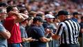 fans reacting, camera crew scrambling, and a ring referee staring at a phone.