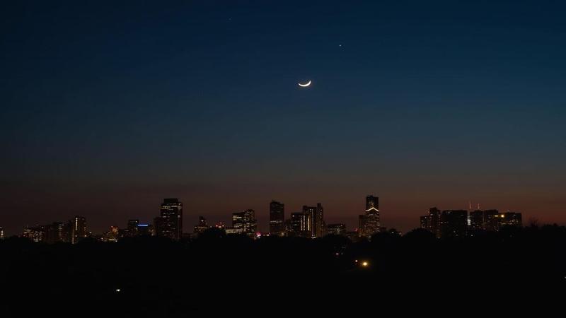 Close-up of the waxing crescent hovering above a city skyline, Spica twinkling nearby, light pollution trying and failing to RSVP for relevance.
